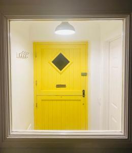 una puerta amarilla es vista a través de una ventana en Yellow door cottage en Moville