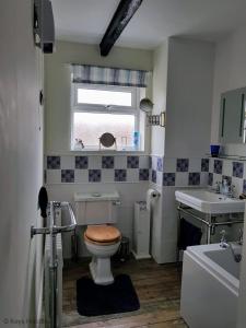 a bathroom with a toilet and a sink and a window at South Side in West Runton