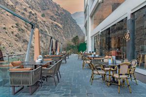 a restaurant with tables and chairs with mountains in the background at Echor Palm Bliss Riverside Resort & Spa Kasol in Kasol