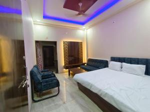 a bedroom with a bed and a couch and a chair at Hari Har HOME STAY FULLY AC in Ujjain