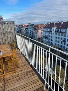 d'un balcon en bois avec une table et une vue sur les bâtiments. dans l'établissement Le Brasilia - Appartement neuf pour 4 personnes avec terrasse, à Strasbourg
