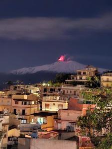 una montaña cubierta de nieve en el fondo de una ciudad en Sciala', en Taormina