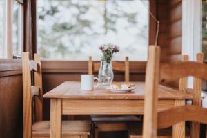 a wooden table with a vase of flowers and a plate of food at Rural Log Cabin in Snowdonia - 2 Bedrooms & Parking in Ffestiniog