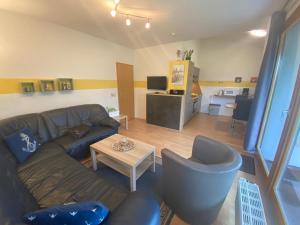 ein Wohnzimmer mit einem Sofa, Stühlen und einem Tisch in der Unterkunft Ferienhaus Seepferdchen in Sehestedt
