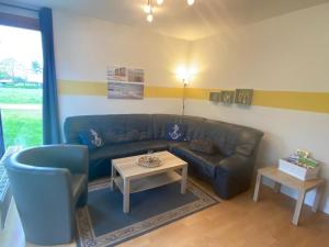 un soggiorno con divano blu e tavolo di Ferienhaus Seepferdchen a Sehestedt
