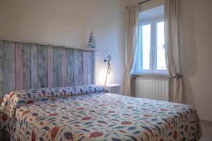 a bedroom with a bed with a floral bedspread and a window at L'acciughina in Portoferraio