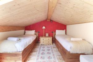 two beds in a room with red walls and wooden ceilings at Clos des Vorgeats - Duplex Beside Golf Course - Patio - UTMB in Chamonix-Mont-Blanc