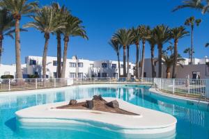 a large swimming pool with palm trees in the background at Grandes Playas Haven in Corralejo