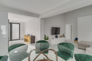 uma sala de estar com uma mesa de vidro e cadeiras verdes em Graça House em Machico