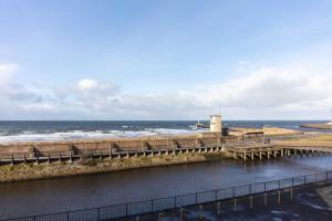 ein Pier am Strand mit dem Ozean im Hintergrund in der Unterkunft The Original Donnini Apartment in Ayr