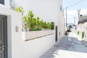a white building with plants on the side of a street at Nostos Apartments Fira in Fira