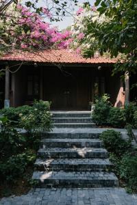 a set of stairs in front of a building with pink flowers at TOKI Retreat Vân Long in Ninh Binh
