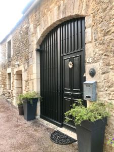 una porta nera su un edificio di pietra con piante in vaso di Le Prieuré de l'Auxois a Alise-Sainte-Reine