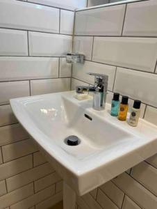 um lavatório branco numa casa de banho com azulejos brancos em Studio très pratique ! em Le Mont-sur-Lausanne