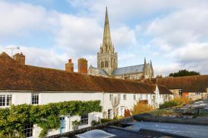 uma igreja com um campanário numa cidade com edifícios em Canon Gate em Chichester