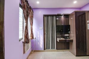 a room with purple walls and a door with a television at FabExpress Laxmi Inn in kolkata