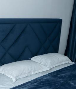 a bed with a blue headboard and a white pillow at Евродвушка в ЖК Каратал in Kostanay