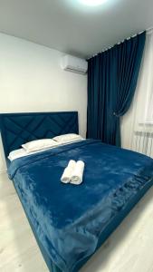 Una cama azul con dos toallas blancas. en Евродвушка в ЖК Каратал en Kostanái
