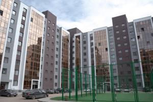 a row of buildings with cars parked in a parking lot at Евродвушка в ЖК Каратал in Kostanay