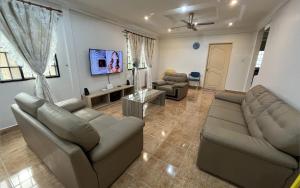 a living room with two couches and a flat screen tv at [El Casa] Homestay Miri (8 Pax) in Miri