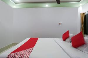 a white bed with red pillows in a room at OYO Flagship 67063 Roy Villa Resort in Baharampur