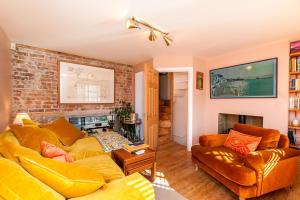 a living room with a yellow couch and a brick wall at Coastal Gem With Hot Tub in Kent