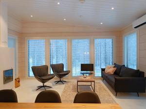 - un salon avec un canapé, des chaises et des fenêtres dans l'établissement Tuikku, à Syöte