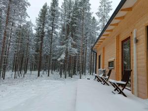 une véranda enneigée d'une cabine avec deux bancs dans l'établissement Tuikku, à Syöte