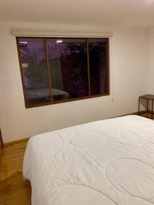 a white bed in a room with a window at Suite Eugenia ubicada en el centro de Estreno in Cuenca