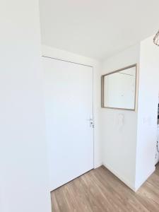 Dieses weiße Zimmer verfügt über eine Tür und einen Spiegel. in der Unterkunft Moderne et charmant T2 in Villiers-le-Bel