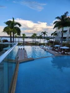 a large swimming pool with palm trees and a building at Luxuoso Flat Brisas do Lago Terraço Aconchegante in Brasilia