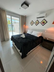 a bedroom with a large bed with a black blanket at Luxuoso Flat Brisas do Lago Terraço Aconchegante in Brasilia