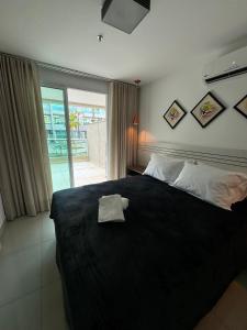 um quarto com uma cama preta com uma toalha em Luxuoso Flat Brisas do Lago Terraço Aconchegante em Brasília