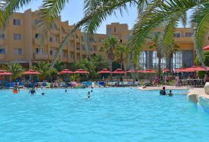 a pool at a resort with people in the water at Skanes Sérail in Monastir