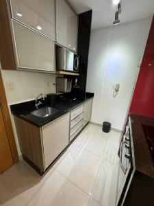 a small kitchen with a sink and a microwave at Luxuoso Flat Brisas do Lago Terraço Aconchegante in Brasília