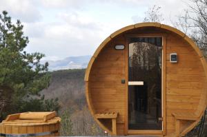 a wooden sauna with a glass door in the woods at Üveghuta Vendégház in Vágáshuta