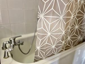 - un rideau de douche dans la baignoire revêtue de carrelage blanc dans l'établissement Suite Jason, à Villeurbanne