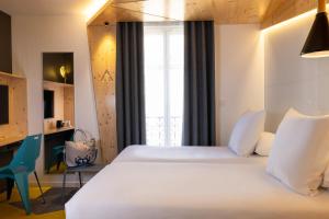 a bedroom with a large white bed and a desk at Urban Bivouac Hotel in Paris