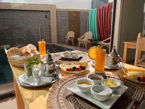 a breakfast table with food and orange juice on it at Beach Side Imsouane in Imsouane