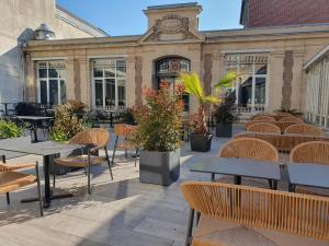 a patio with tables and chairs in front of a building at Hôtel Spa Marotte in Amiens