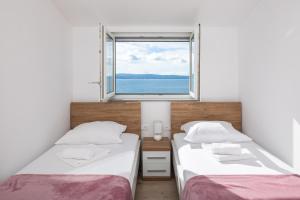 two beds in a room with a window at Prestige Apartments in Jesenice