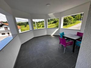 a room with a table and chairs and windows at PJ Motel Pilot in Cazin