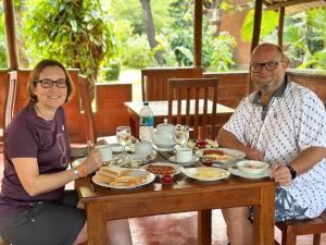 un hombre y una mujer sentados en una mesa con comida en Sigiriya Cottage en Sigiriya