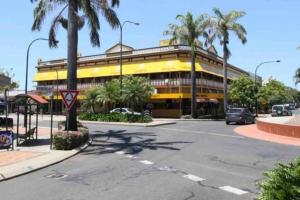 a yellow building with palm trees in front of a street at Island Villas - Lady Elliott - Unit 2 in Bundaberg