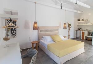 a white bedroom with a bed and a chair at Malibu Suites in Lassi