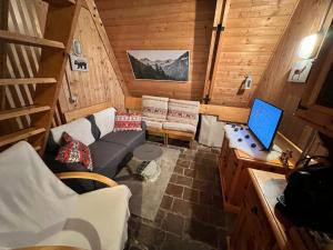 a small living room with a couch and a laptop at ~Chalet_Rifugio tra i boschi~ in Sella Nevea
