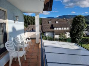 Un balcón con sillas blancas y vistas. en Tannenblick, en Zell am Harmersbach