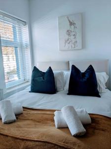 a white bed with blue pillows in a room at Cardiff 2 Bedroom Luxury House in Cardiff