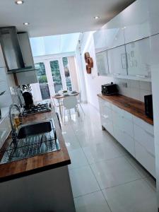 a white kitchen with a sink and a counter at Cardiff 2 Bedroom Luxury House in Cardiff