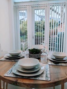 a wooden table with plates and dishes on it at Cardiff 2 Bedroom Luxury House in Cardiff